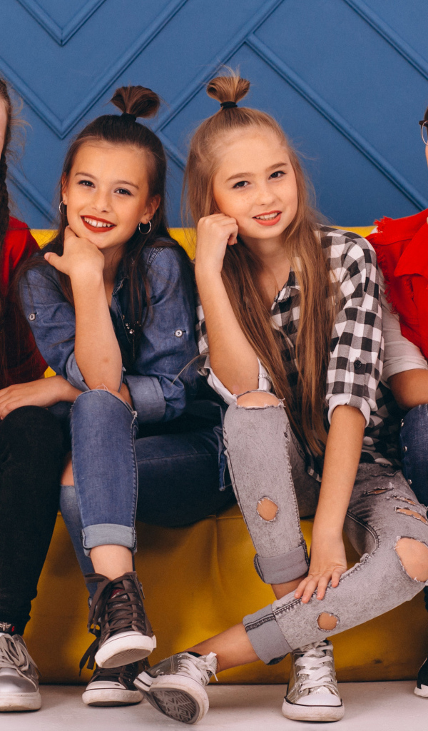 Четыре модных девочки сидят на диване 