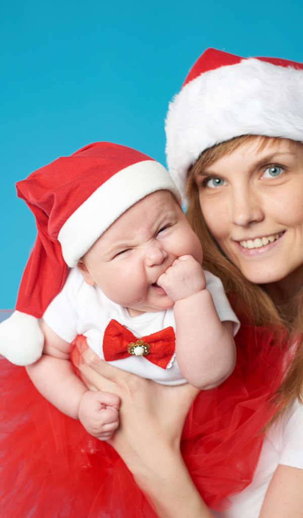 Смешной ребенок в новогоднем костюме на руках у мамы 