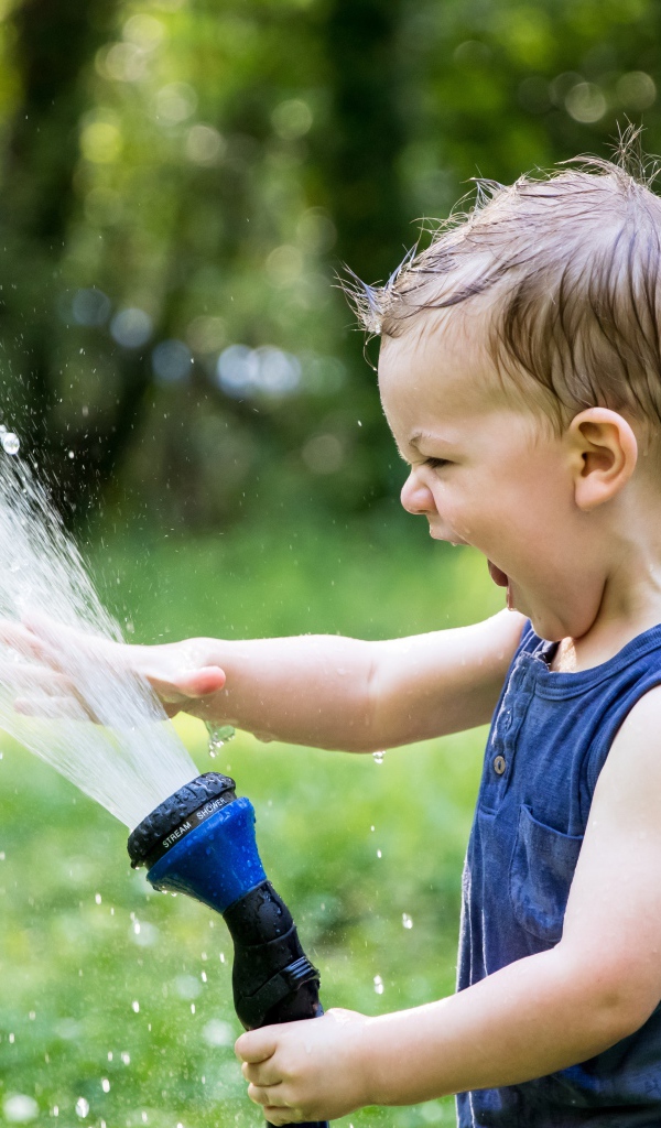 Смешной маленький мальчик играет с водой 