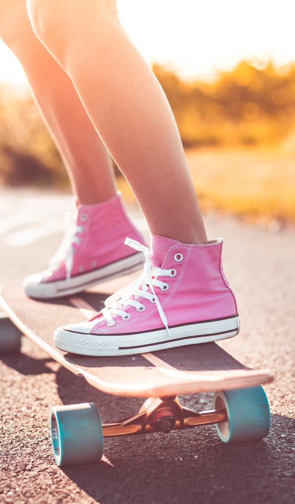 Девочка в розовых кедах едет на скейтборде