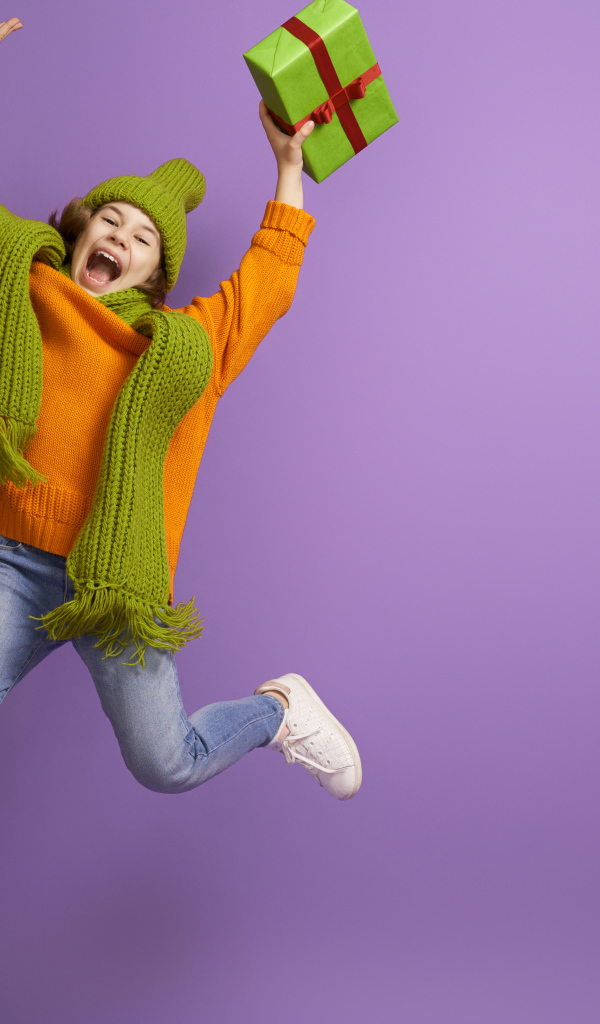 Счастливая девочка с подарком в руке на фиолетовом фоне