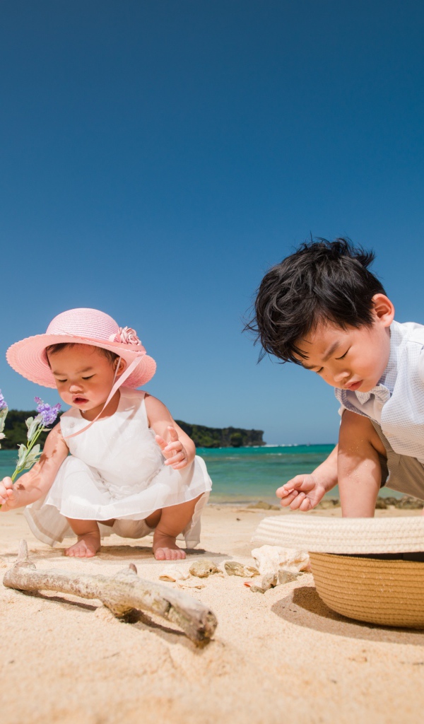 Маленькие дети азиаты играют на песке у моря 