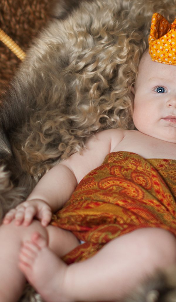 Маленький грудной ребенок в короне лежит в корзине 