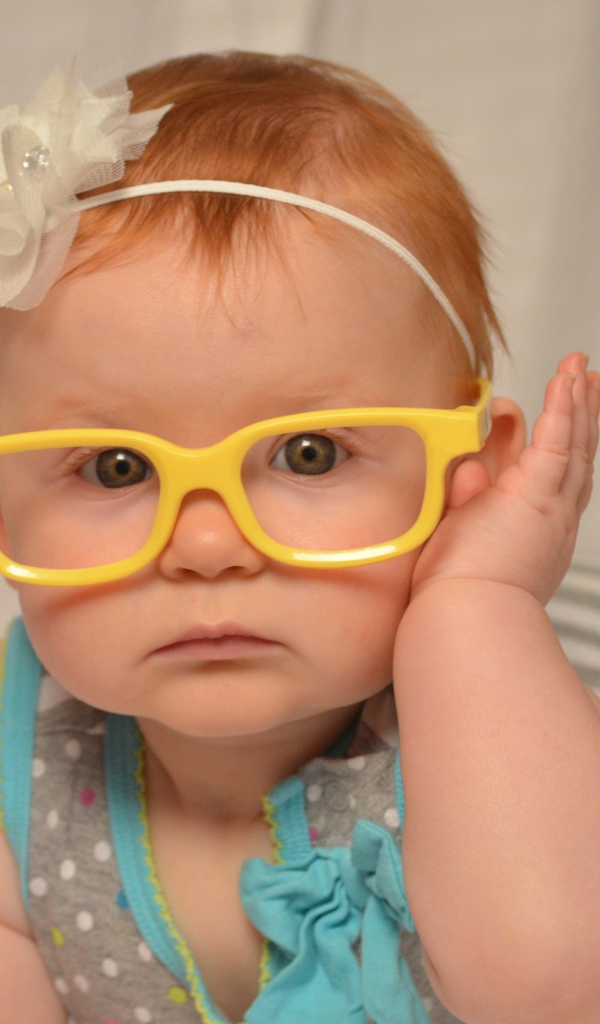 Маленькая красивая девочка в очках с обручем на голове