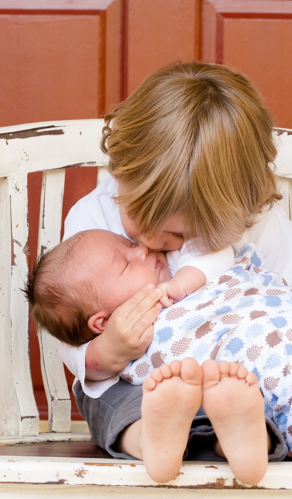 Маленькие мальчик держит брата на руках 