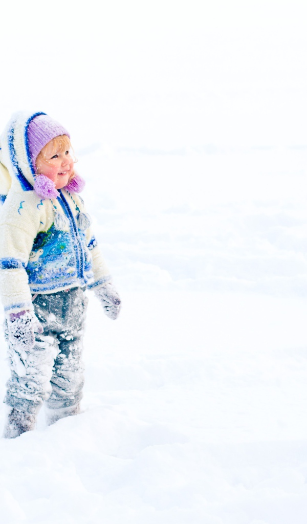 Маленькая веселая девочка гуляет по снегу
