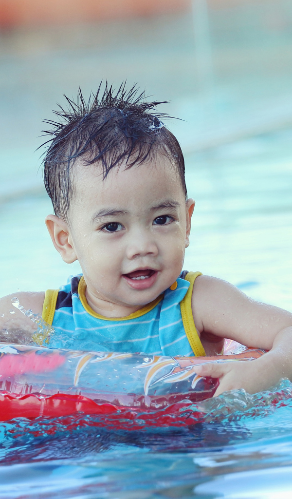 Маленький ребенок со спасательным кругом в бассейне 