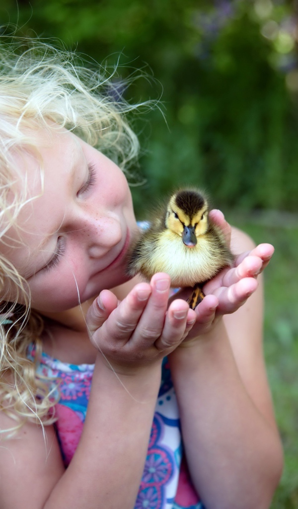 Маленькая милая девочка с утенком в руке
