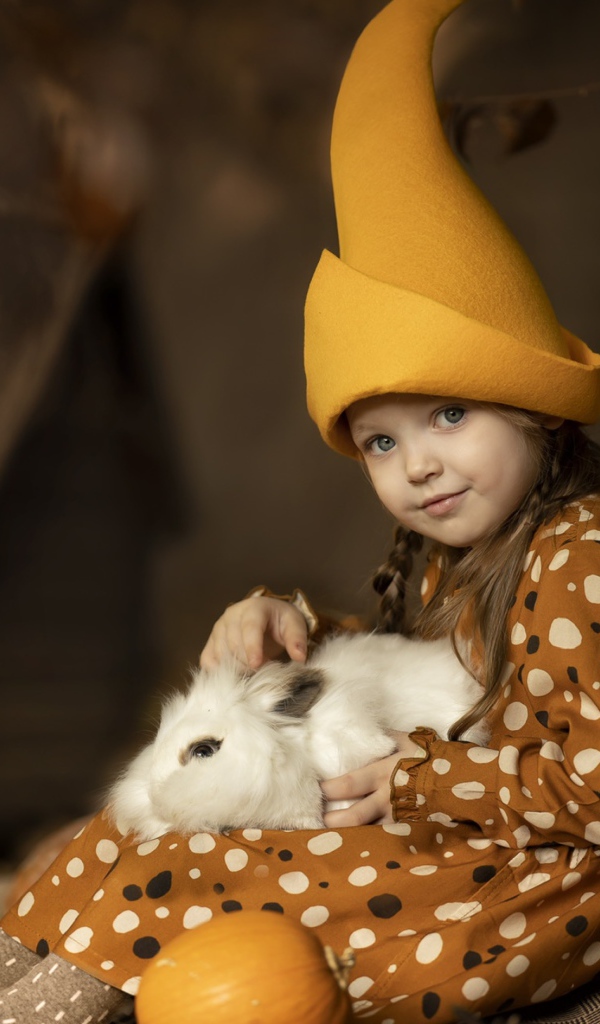 Маленькая смешная девочка в колпаке с кроликом