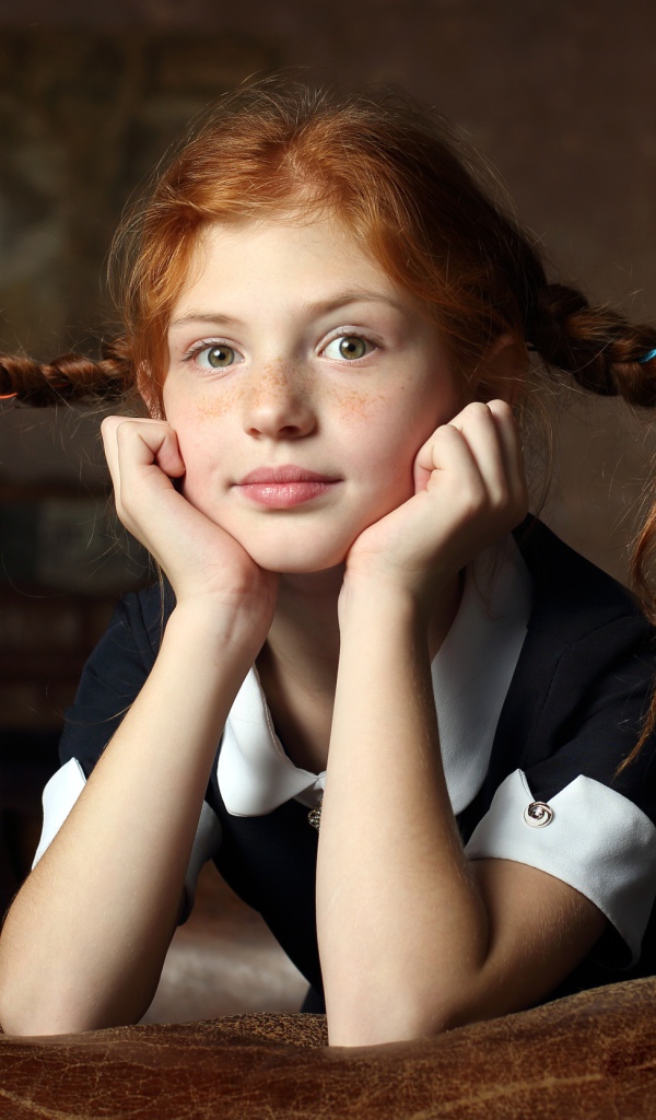 Маленькая смешная девочка с косами в школьной форме 