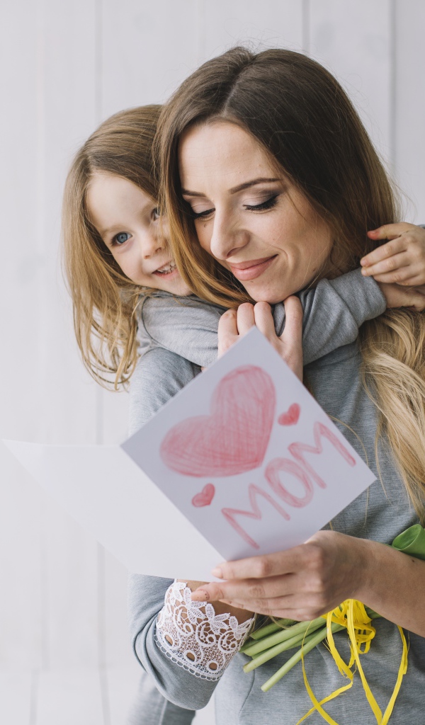 Маленькая девочка подарила маме открытку и букет тюльпанов