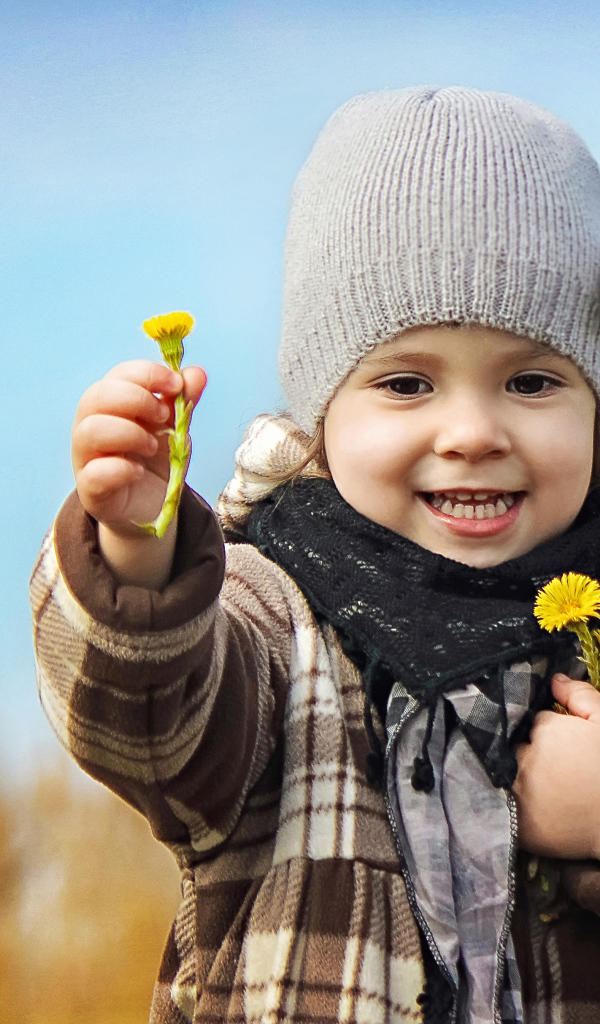 Маленькая девочка в шапке с желтыми цветами в руке