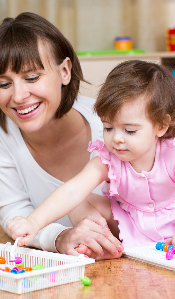 Маленькая девочка в розовом платье играет с мамой