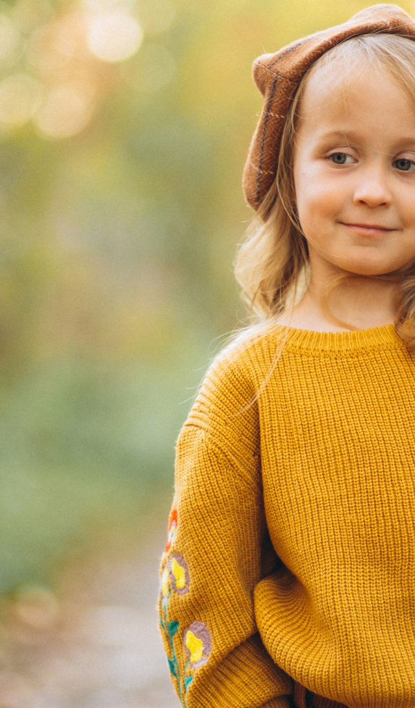 Маленькая девочка в свитере гуляет в лесу