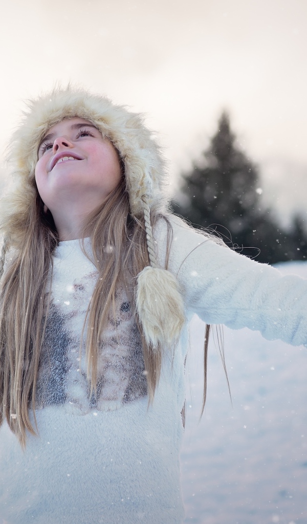 Маленькая девочка в теплой шапке на улице зимой