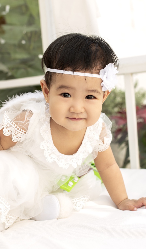 Маленькая девочка в белом платье с леденцом в руке