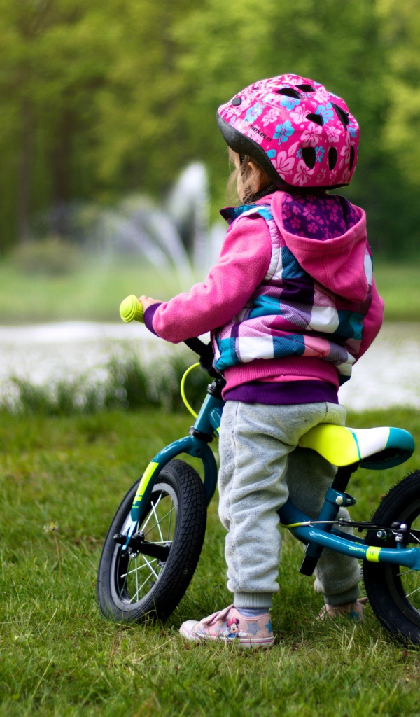 Маленькая девочка на велосипеде в парке 