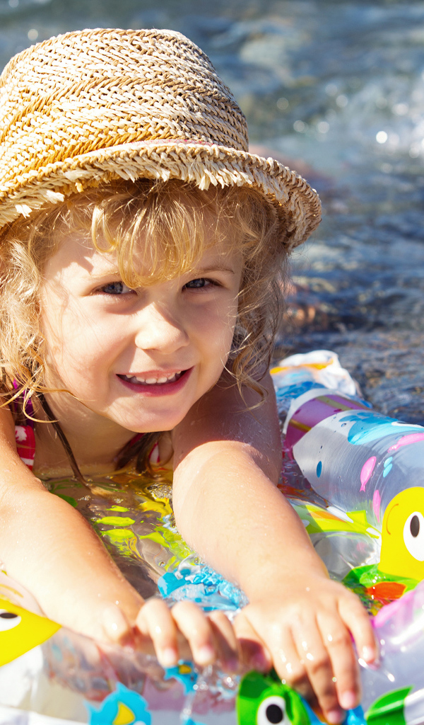 Маленькая девочка на надувном матрасе в воде