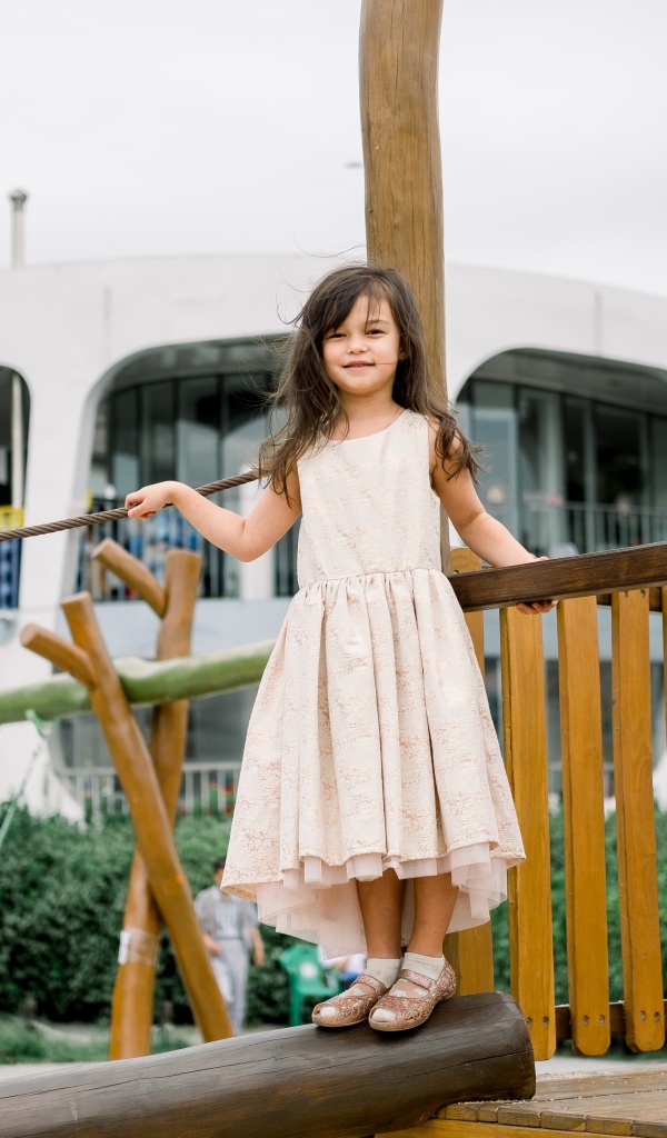 Маленькая девочка стоит на детской площадке 