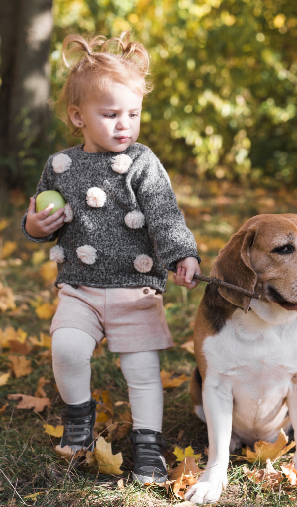 Маленькая девочка гуляет с собакой по осеннему парку