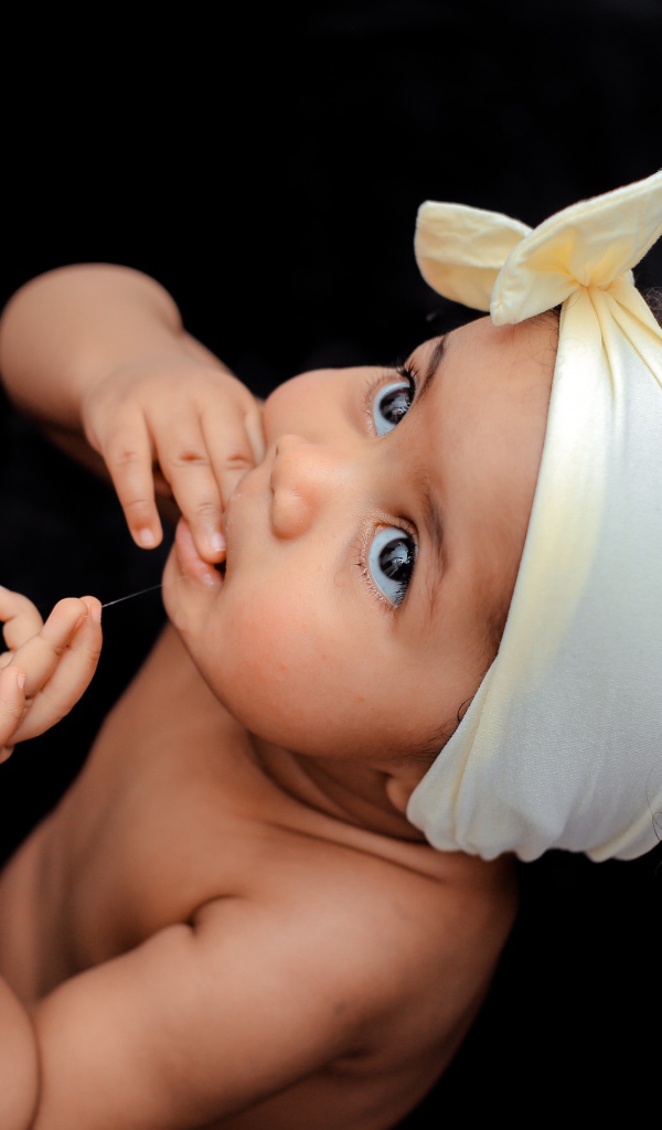 Маленькая девочка с повязкой на голове на черном фоне