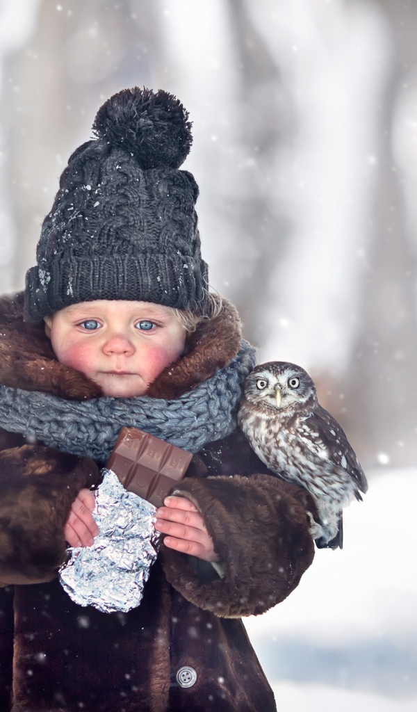 Маленькая девочка с шоколадкой в руках на улице зимой