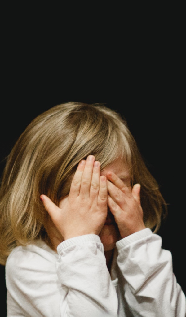 Маленькая девочка с закрытыми глазами на черном фоне 