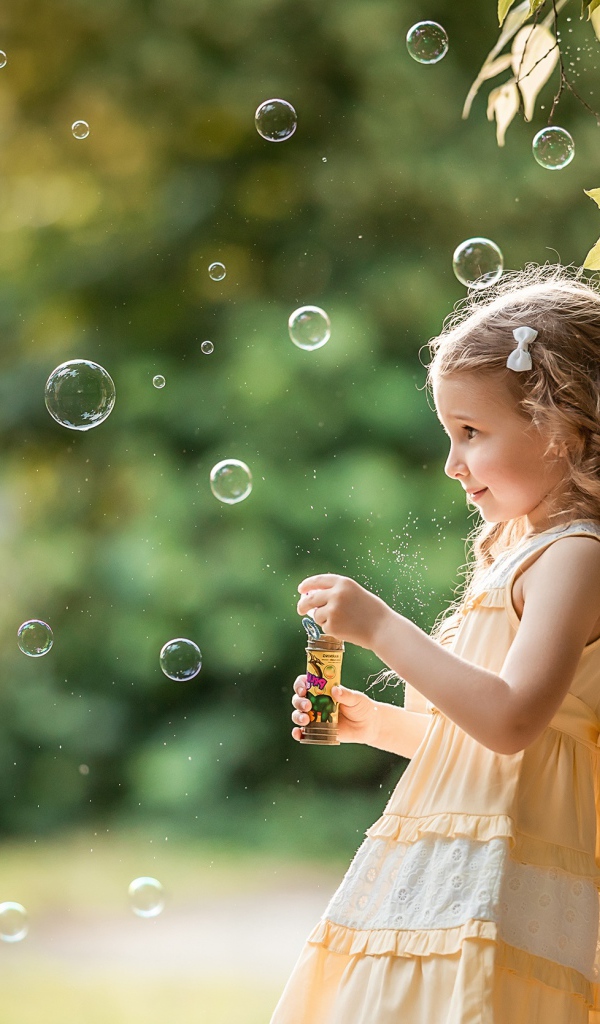 Маленькая девочка с мыльными пузырями в саду 