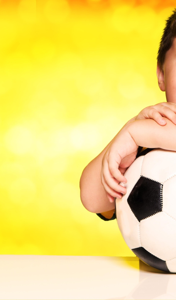 Маленький довольный мальчик с футбольным мячом