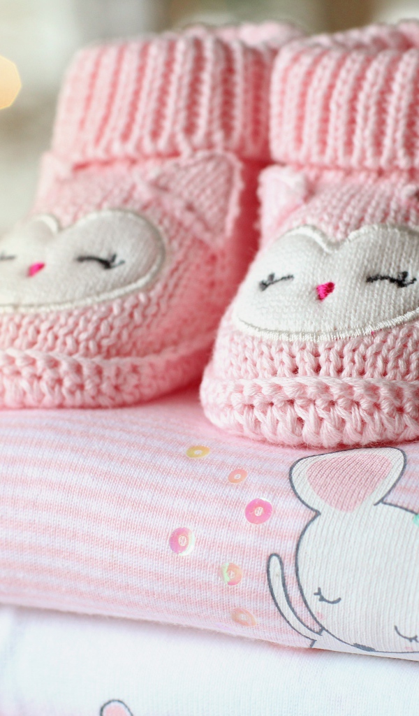Маленькие розовые пинетки и одежда для малыша 
