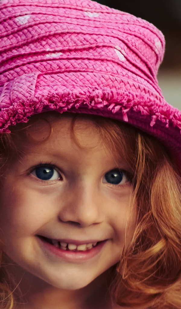 Маленькая улыбающаяся девочка в розовой шляпе