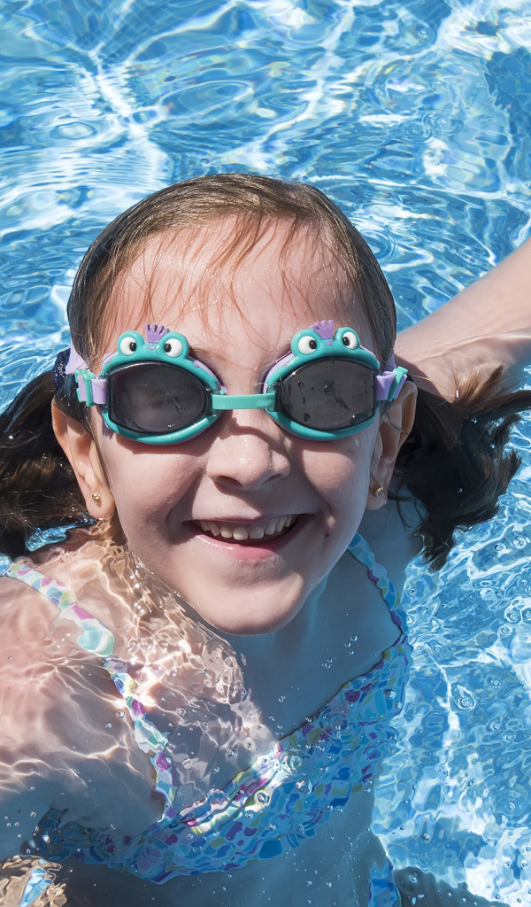 Маленькая улыбающаяся девочка в очках в бассейне 
