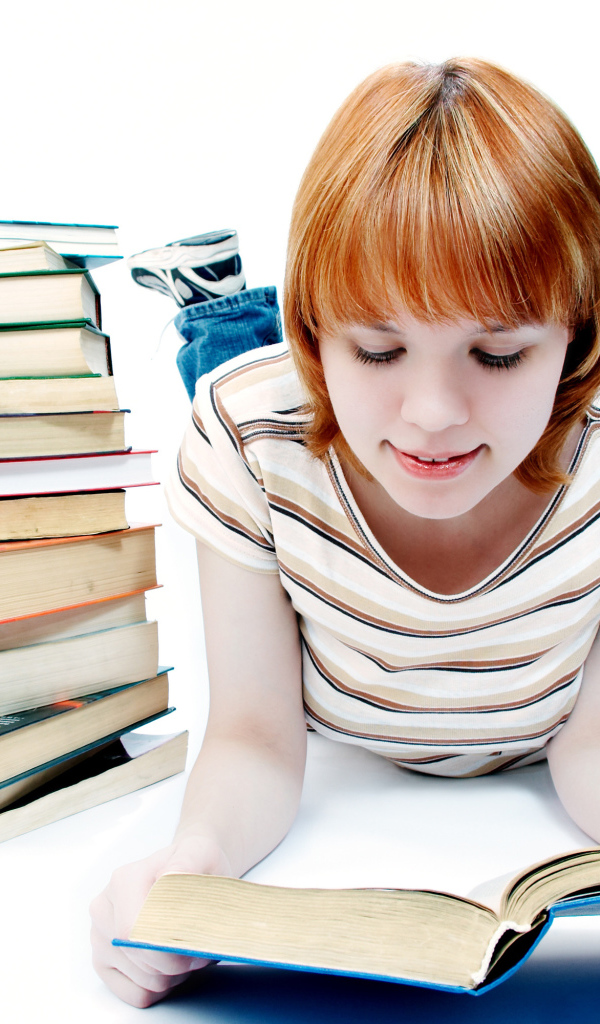 Рыжеволосая девочка школьница читает книги на белом фоне 