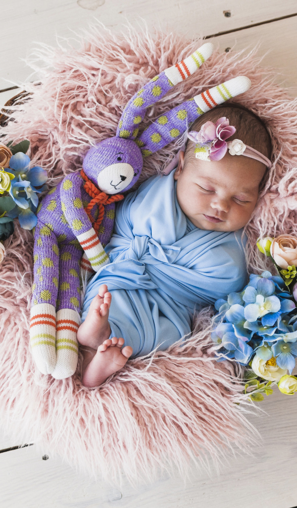 Спящий грудной ребенок с игрушкой в корзине 