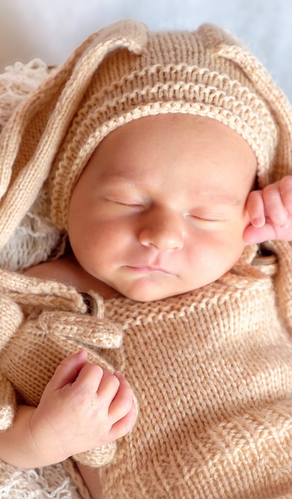 Спящий грудной ребенок в вязаном костюме
