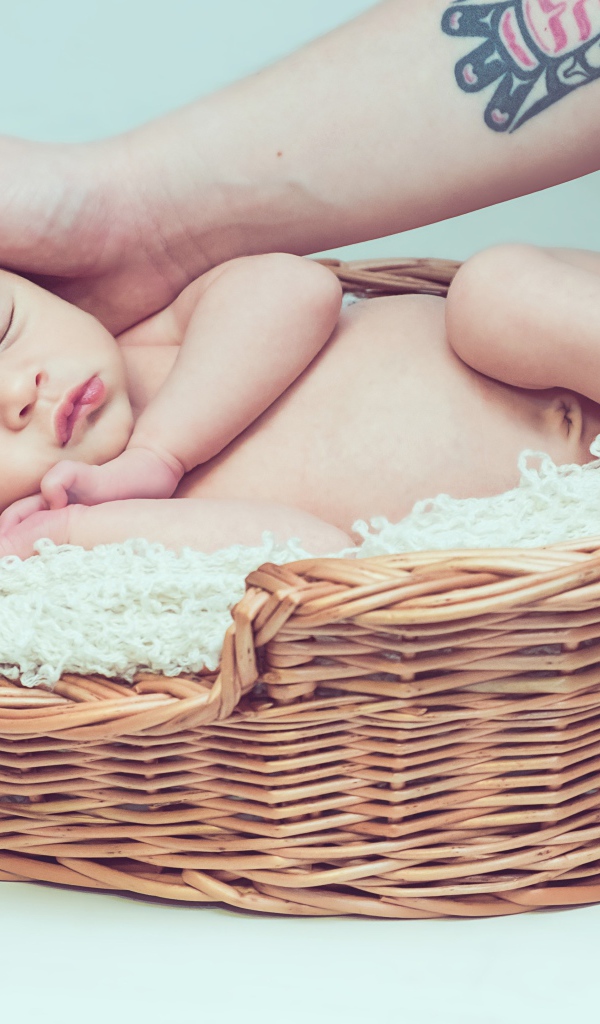 Спящий грудной ребенок в корзине на сером фоне 