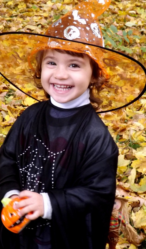 Улыбающаяся девочка в костюме ведьмы на Хэллоуин