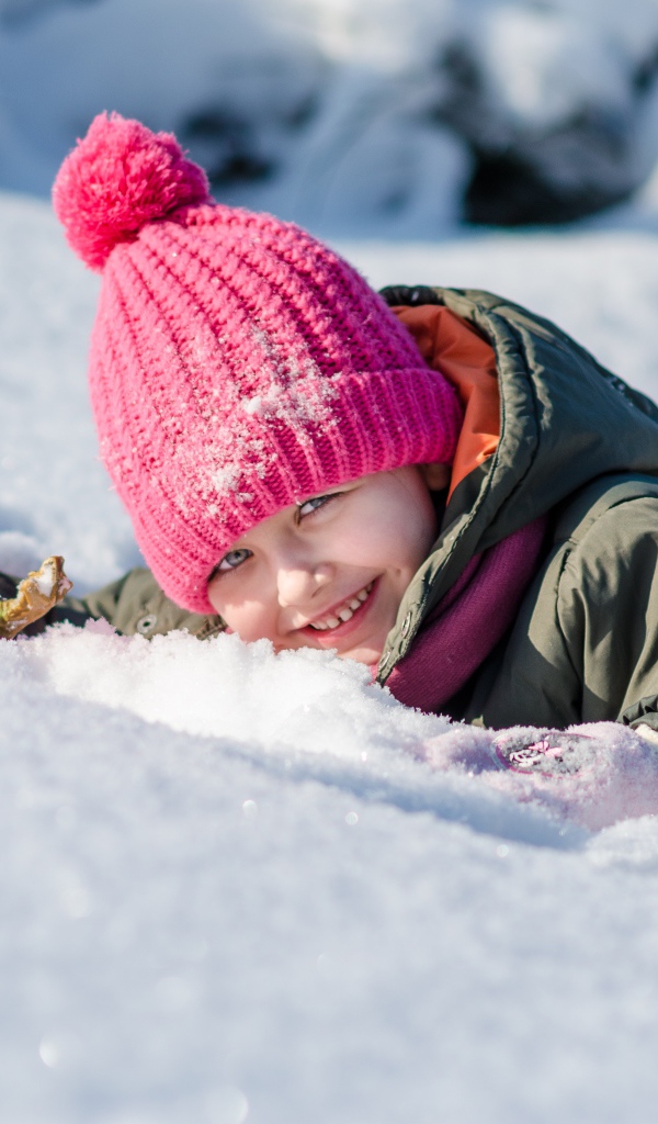 Улыбающаяся девочка лежит на снегу