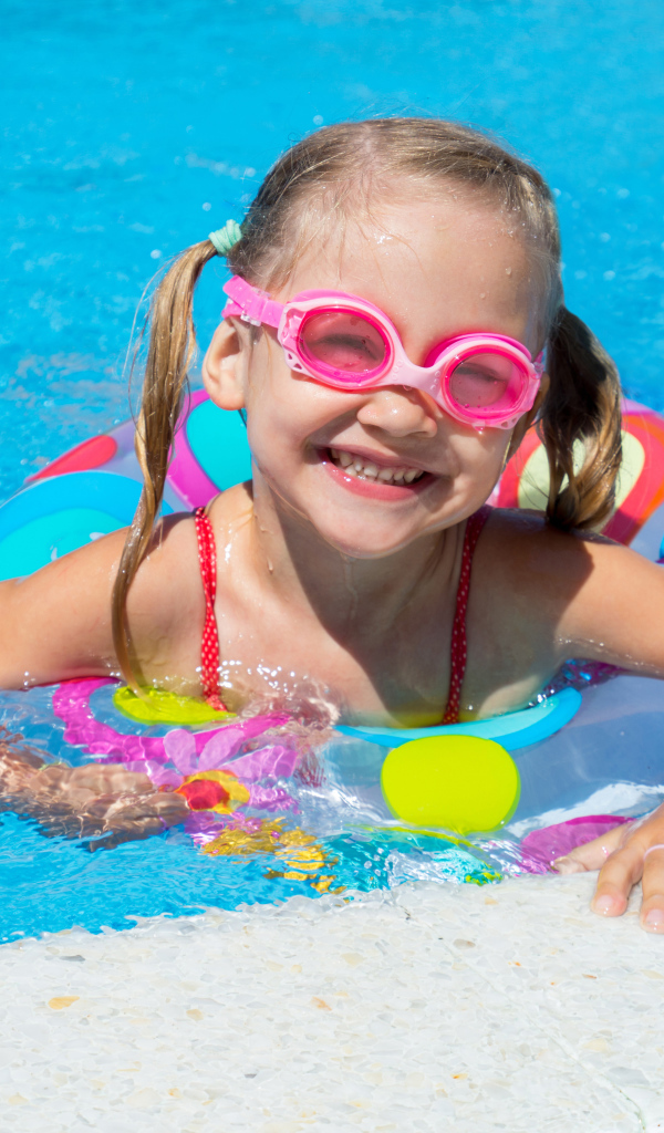 Улыбающаяся девочка с кругом в бассейне 
