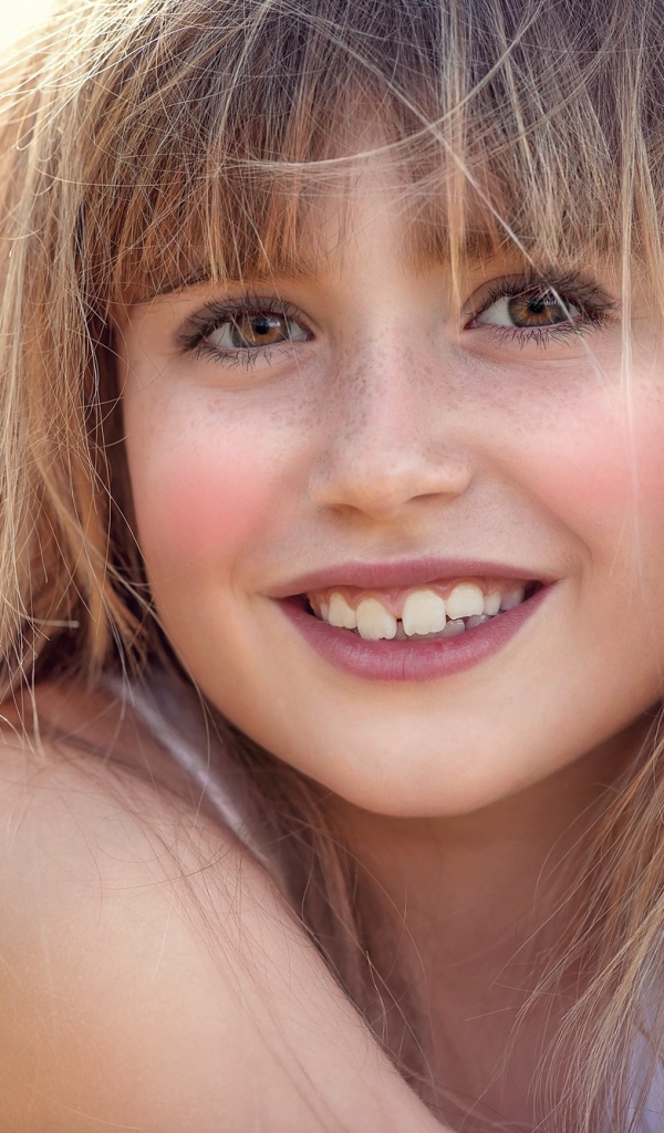 Улыбающаяся девочка с веснушками на лице 