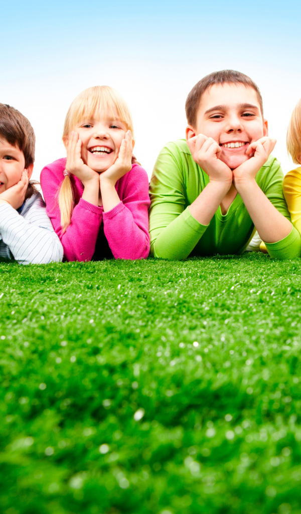 Улыбающиеся дети лежат на зеленой траве