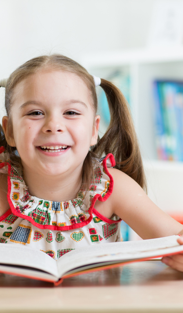 Улыбающаяся маленькая девочка с книгой 