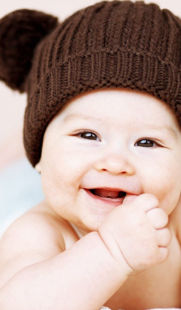 Улыбающийся грудной ребенок в коричневой шапке