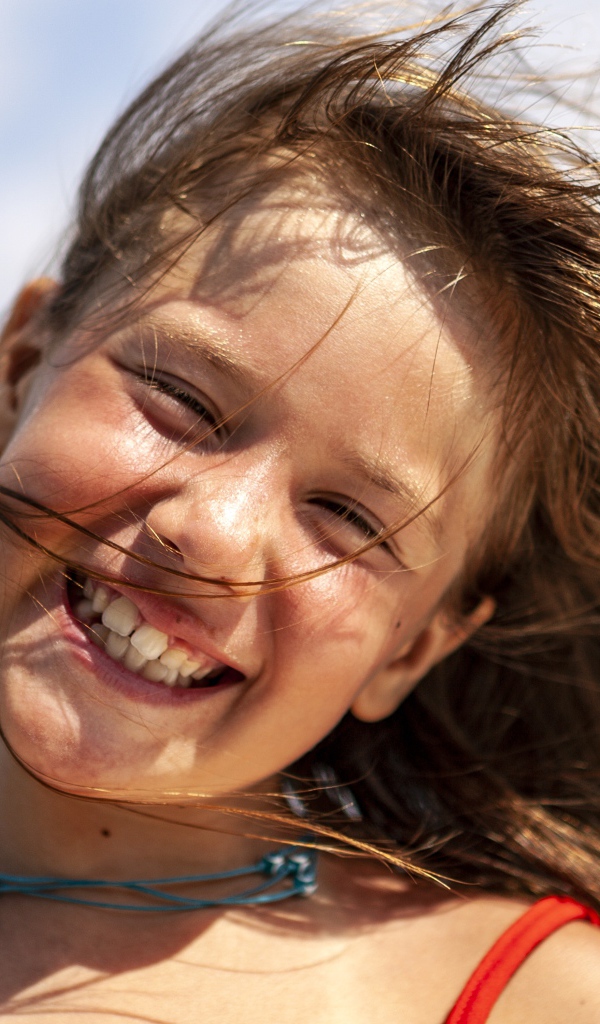 Ветер развивает волосы улыбающейся девочки