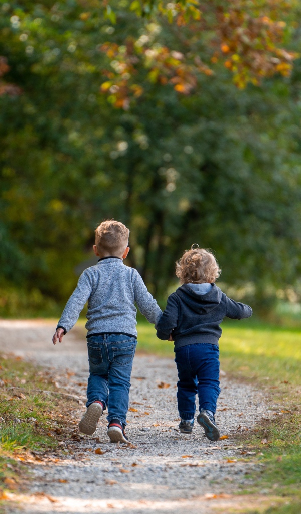 Два маленьких ребенка гуляют в осеннем парке