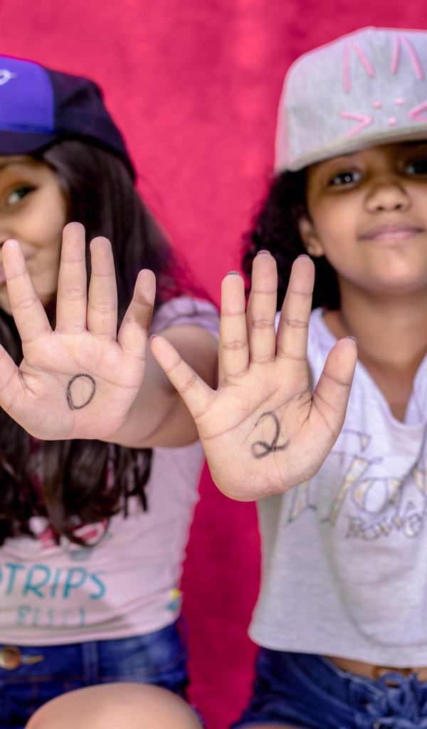 Две маленькие девочка с цифрами на ладонях 