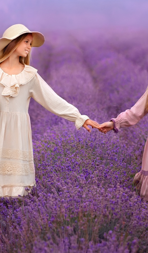Две маленькие девочки идут по лавандовому полю 