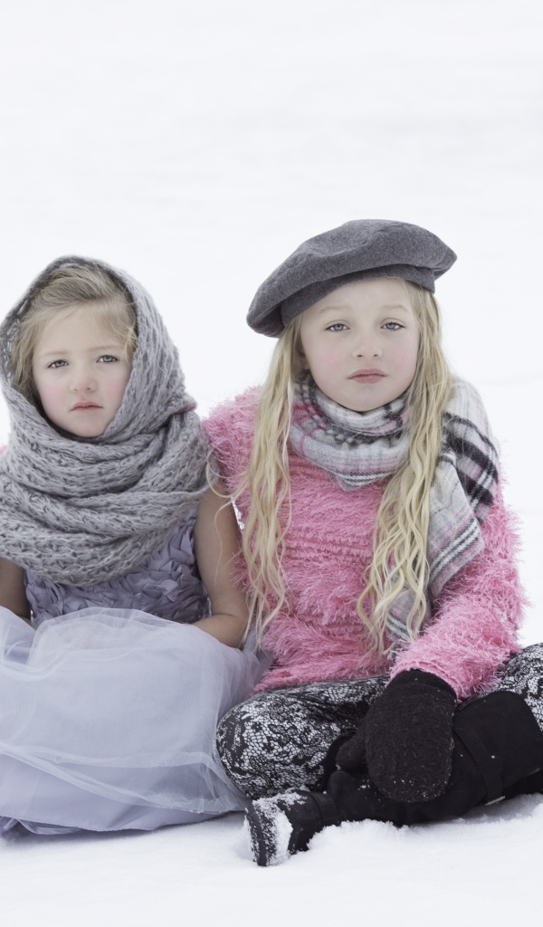 Две маленьких сестры сидят на снегу 