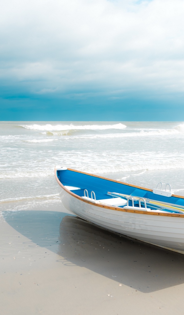 Лодка стоит на белом песке у моря 