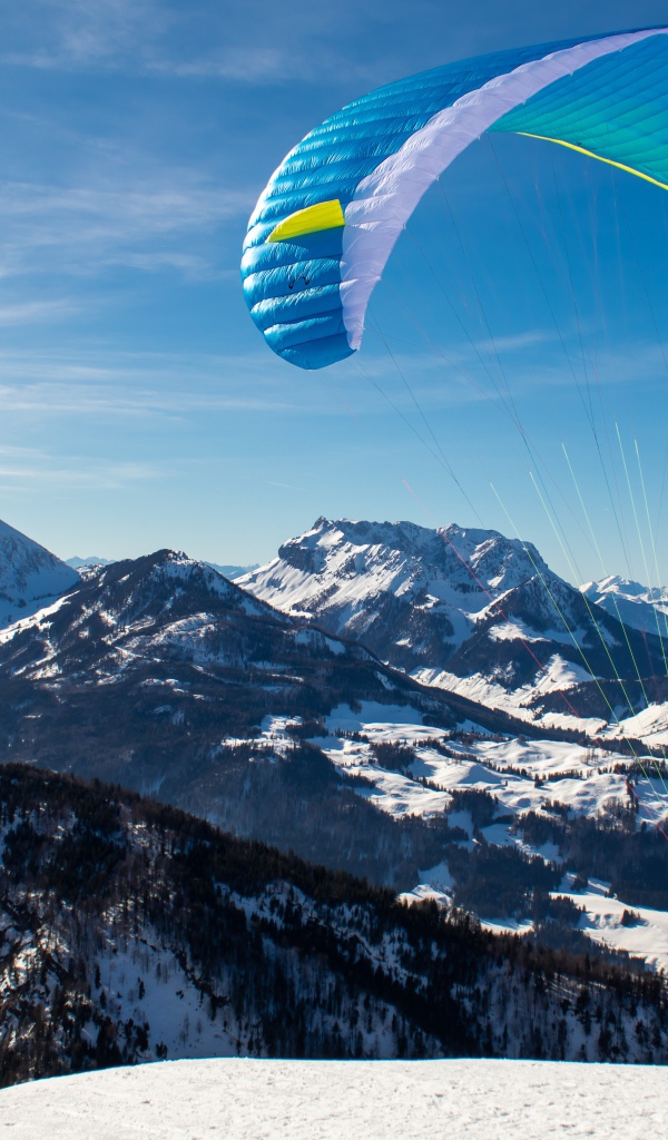 Парапланерист прыгает с горы зимой 